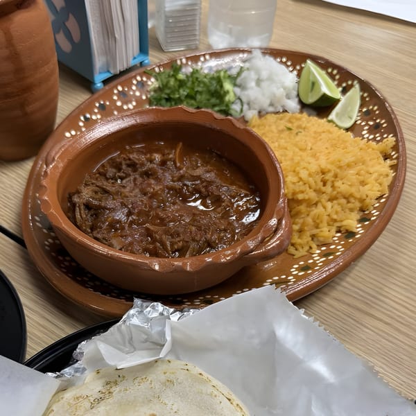 Las Flores Mexican's birria plate with rice, cilantro, onions, limes, and tortillas.